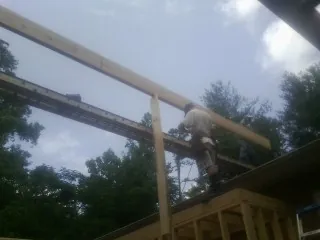 Carpenter setting a ridge beam over a new addition frame — Ice Dam Removal by Roofing Brothers in Rio