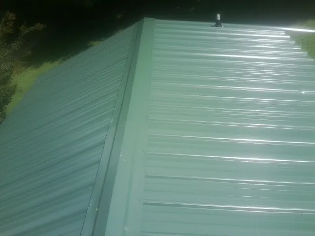 New green metal panels meeting at the ridge of a roof — Flat Roof Repair work by our crew in Rio