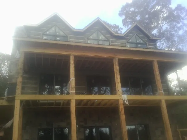 Dormers and porch framing on a large log home under construction — Roof Coating work by our crew in Rio