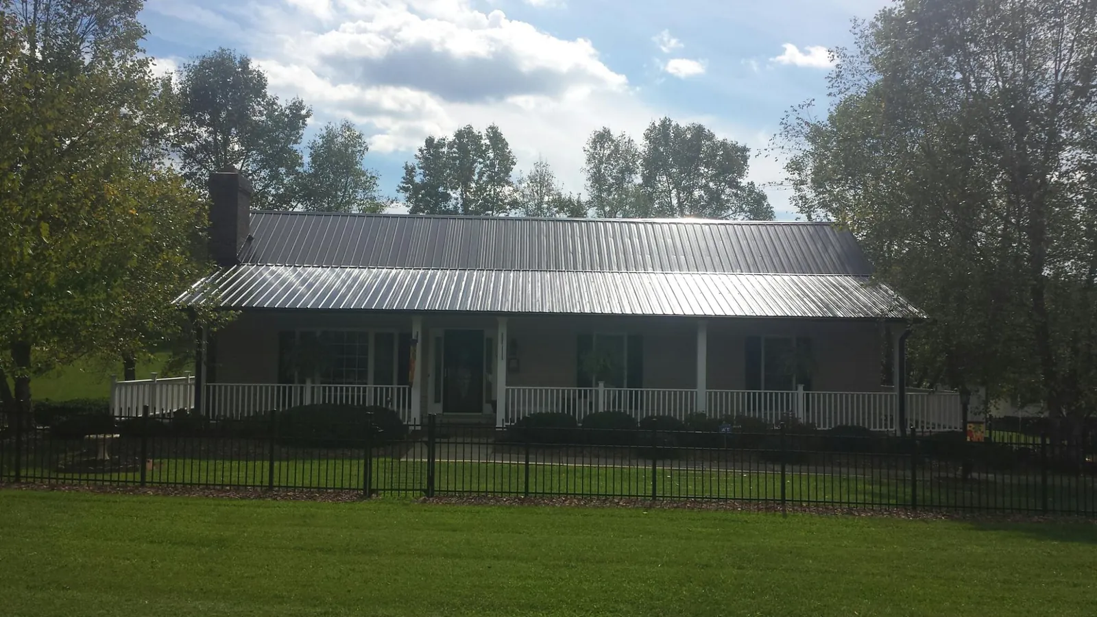 Gray metal roof on a brick ranch with a full width front porch — Gutter Guard Installation work by our crew in Rio