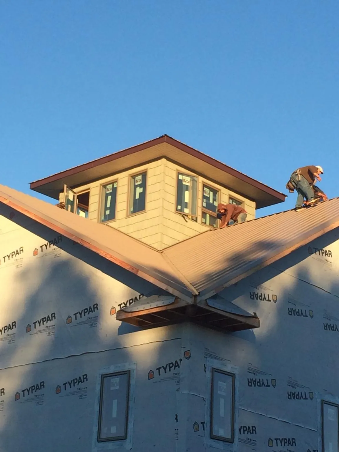 Roofers working around a rooftop cupola on a new metal roof at sunset — Roof Waterproofing in Rio by Roofing Brothers